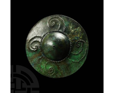 13th-6th century BC. A bronze discoid shield boss with raised and domed centre, with a pearled repoussè border from which fou