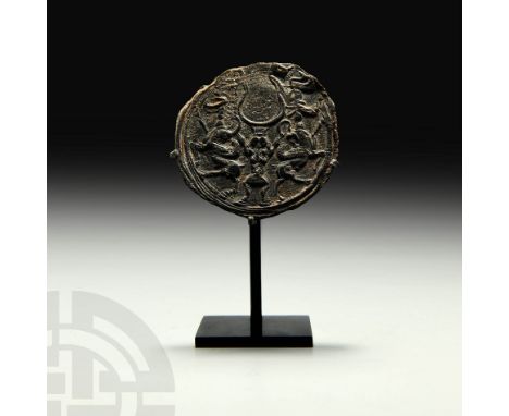 1st millennium BC. A discoid talisman displaying a dynamic scene composed of regardant winged animals (an ibex and a lion) ad