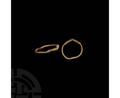 9th-11th century AD. A gold finger ring with round-section hoop, coiled wire sleeves at the shoulders and twisted wire bezel.