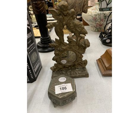 A VINTAGE BRASS ALARM CLOCK WITH ORNATE CHERUB AND STORK DETAIL PLUS A WHITE METAL TRINKET BOX 