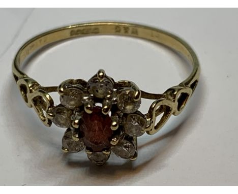 A 9 CARAT GOLD RING WITH A CENTRE RED STONE SURROUNDED BY CUBIC ZIRCONIAS SIZE R 