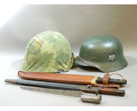 A German WWII steel helmet, a US helmet, two bayonets, and a machete in a leather scabbard