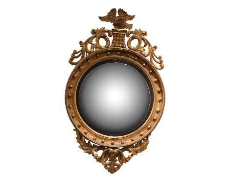 A Regency Carved Giltwood and Gesso Circular Convex Mirror, early 19th century, with ebonised reeded slip and ball-surmounted