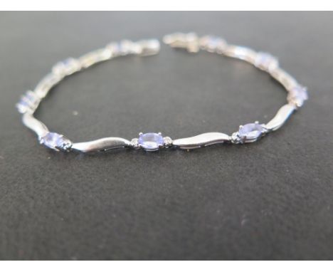 A tanzanite and diamond bracelet - With curved bar spacers and two diamond highlights - Stamped 14K - Length 18cms - Weight a