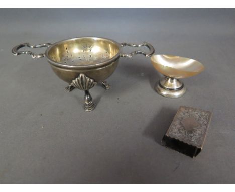 A hallmarked Brittania silver tea strainer on stand - the stand on three legs with shell shaped knees and stepped hoof feet -