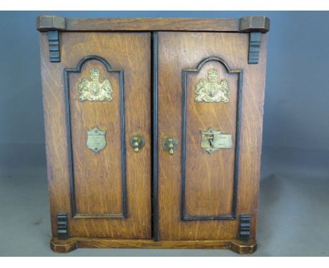 An oak cased smokers cabinet with twin doors opening to reveal drawers and pipe shelf, cigar cutter etc - Height 31.5 cm x Wi