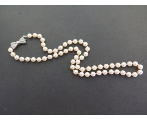 A cultured pearl single-row necklace to the partial platinum diamond bow-shape clasp - Set with brilliant and single-cut diam