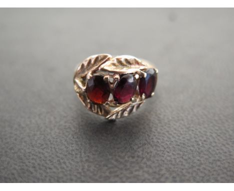 A garnet three-stone ring - With foliate detail - Stamped 9ct - Ring size R - Weight approx 5.6gms
Condition Report: Good to 