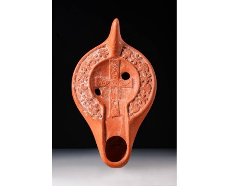 Ca. AD 300 - 500.A red terracotta oil lamp with a sunken discus displaying a Latin cross adorned with circular and rhomboid d