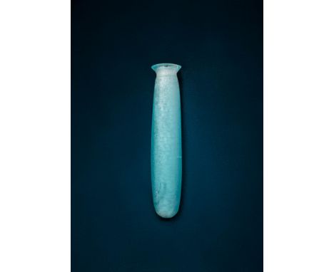 Ca. 7th century BC.A translucent blue glass alabastron with an elongated cylindrical body tapering gently to a rounded base. 