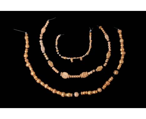 Ca. 100 BC - AD 200.A collection of beads encasing gold foil beneath a transparent glass layer, strung in three separate stra