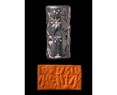 Ca. 8th century BC. A blackish stone cylinder seal with two winged genii flanking a Marduk standard. Other astral images in t