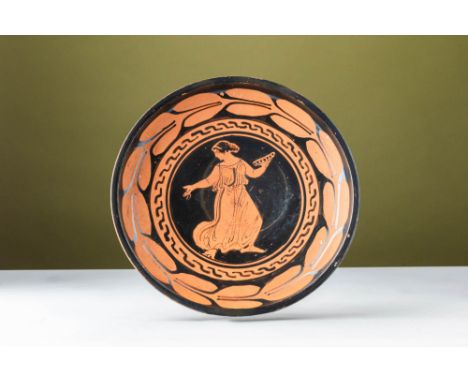 Ca. 400 - 300 BC. A red-figure plate with a broad, shallow body supported by a low ring base. The central tondo is framed by 