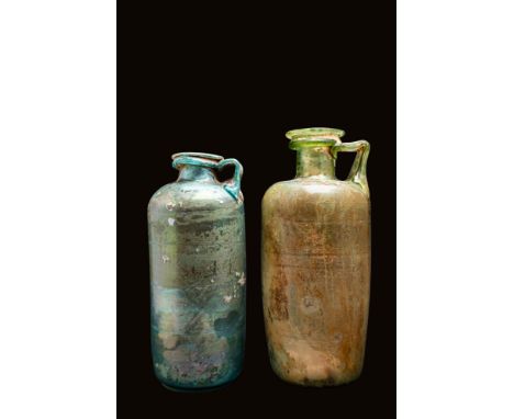 Ca. AD 100 - 300 .A pair of pale green and blue glass bottles. The vessels have a flat base and a cylindrical body with a lig