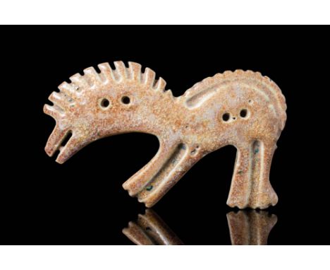 Ca. 9th - 8th century BC. A faience horse-shaped plaque depicting a stylised equine figure with an elongated, curving body an