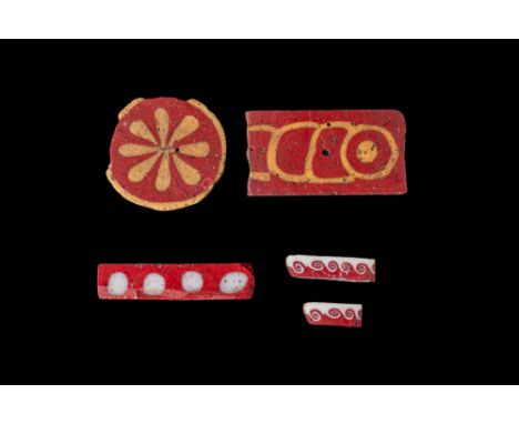 Ca. 300 BC - AD 100. A collection of glass inlays and bars. The first, in the top left corner, is a circular inlay with a red