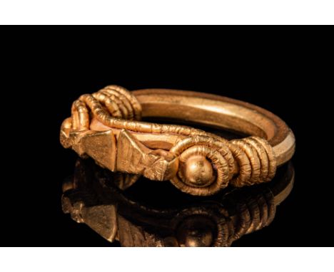 Ca. 100 BC - AD 100. A gold ring with a solid circular hoop of faceted profile. The bezel consists of two axe-shaped elements