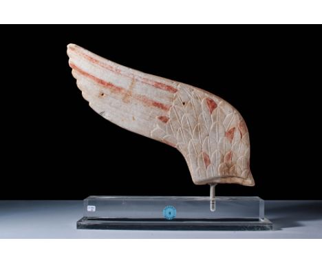 Ca. 5th century BC. A marble wing with an elongated, curved form tapering to a rounded tip. The front surface is decorated wi
