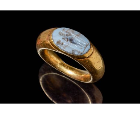 Ca. 200 BC.A gold 23 ct ring with a D-section hoop enlarged on the shoulders to form an oval bezel securing a carnelian intag