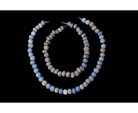 Ca. 370 - 30 BC. A collection of two strings of glass eye beads, composed of predominantly blue annular and spherical shapes.