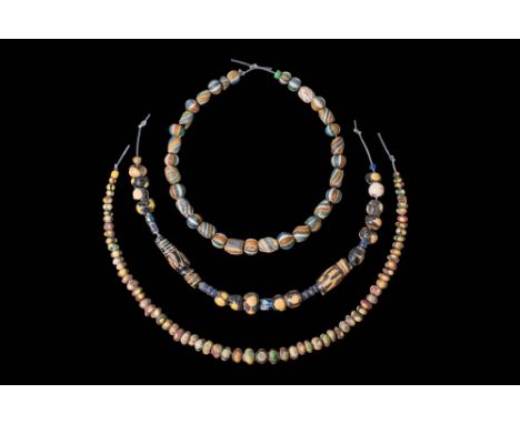 Ca. 400 - 300 BC.A collection of three strings of glass beads, including spherical, cylindrical, and biconical forms, with su