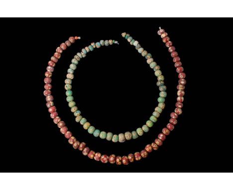 Ca. 370 - 30 BC.A collection of two strings of glass eye beads, one composed of green beads and the other of red. Each bead i