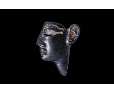 New Kingdom, Ca. 1550 - 1069 BC. A black glass face inlay depicting a profile view of a human head with a pronounced jawline 