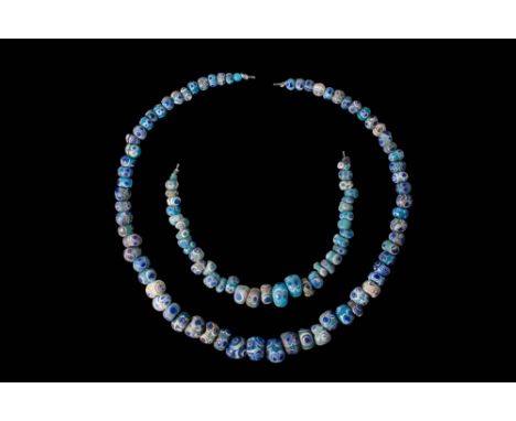 Ca. 330 - 30 BC.A collection of two strings of glass eye beads, composed of predominantly blue annular and spherical beads. E