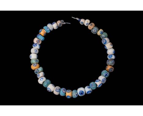 Ca. 330 - 30 BC. A string of glass eye beads in an annular shape, decorated with circular eye motifs composed of concentric r