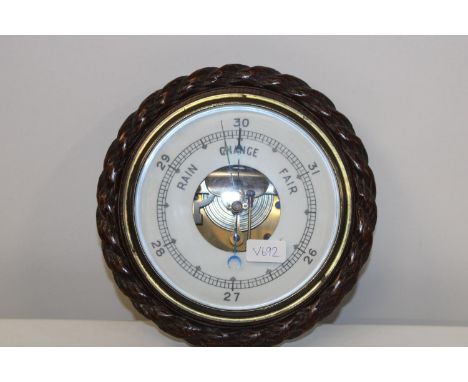 An antique barometer in an oak case with rope detailing 28cm in diameter 