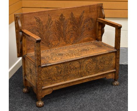 A CARVED OAK MONKS BENCH, 107cms wide