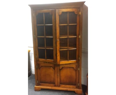 An oak two door Tudor furniture bookcase/display cabinet, pair of paneled glazed doors, triple shelf interior, above slide sh