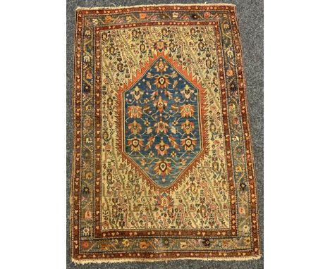 An Antique Persian rug, central geometric floral lozenge with blue ground, within cream intricately patterned panel, all surr
