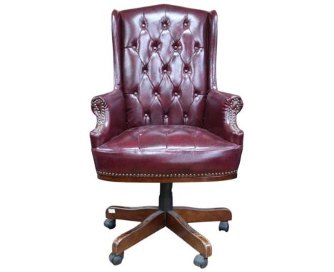 A 20th century red leatherette button upholstered swivel desk chair with wing back over scrolled arms on pentapedal base, 120