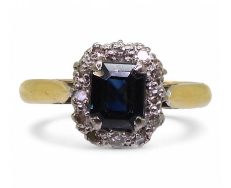 An 18ct gold sapphire and diamond cluster ring, set with a step cut sapphire of approx 6mm x 5mm, made by Cropp &amp; Farr Lt