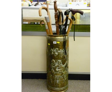 Repousse brass stickstand and contents including a modern folding shooting stick, a Malacca cane with embossed white metal to