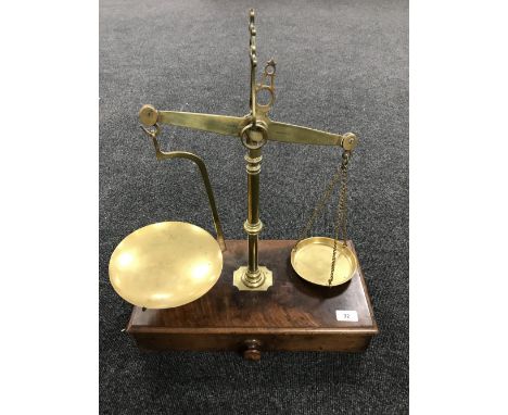A set of Victorian brass balance scales on mahogany base fitted a drawer with weights by Barlett of Newcastle 