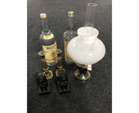 An Aladdin chrome oil lamp with glass chimney and shade, two Bells 4.5 litre empty whiskey bottles, pair of brass candlestick
