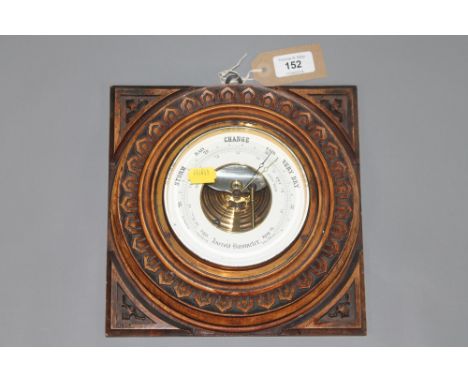 An aneroid barometer in a carved oak frame