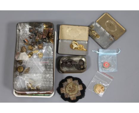 A tin containing a collection of military badges, buttons, patch, etc