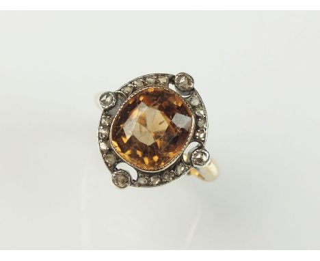 An early 20th century zircon and diamond cocktail ring, designed as a central cushion cut orange zircon milligrain set in yel