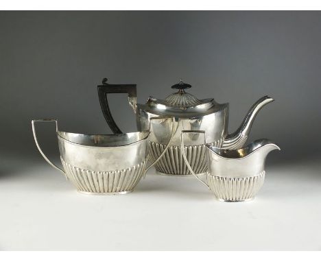 An Edwardian three piece silver tea service, George Nathan & Ridley Hayes, Chester 1902, each piece of oval half reeded form,