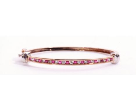 9ct gold ruby and diamond hinged bangle, the top section alternate channel set with 14 round cut small rubies and 13 small di