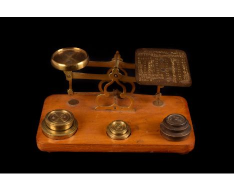 A set of brass postal scales, mounted on wooden plinth with weight recesses containing brass weights, together with a small  