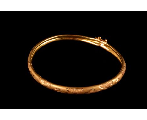 A modern Middle Eastern yellow metal bangle, having satin finish with heart shaped engraved designs, marked 916, approx 11g
