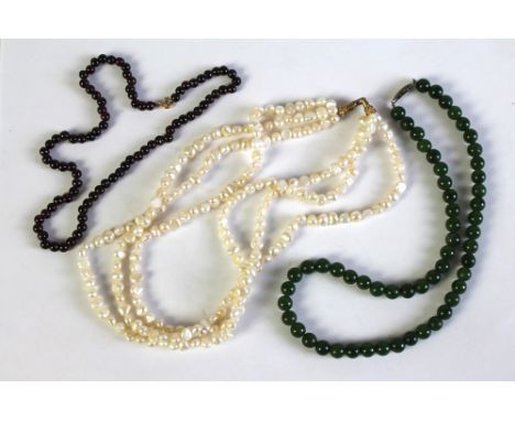 A green jade bead necklace, a freshwater pearl necklace and another.