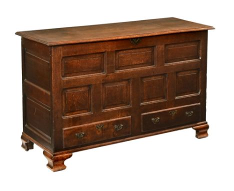 An early 19th century oak mule chest, the top with moulded edge above a panelled front and fitted with two drawers with brass