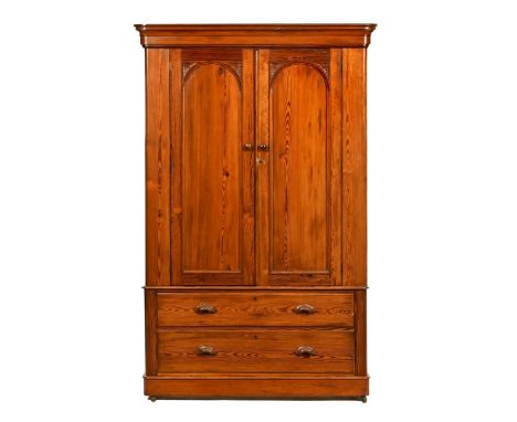 A Victorian pitch pine wardrobe, with a pair of arched doors with foliate carving opening to hanging space to either side, th
