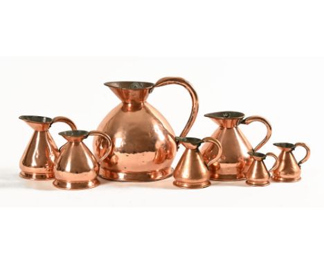 A collection of seven copper jugs, one marked Imperial Customs 1826 and stamped with a military broad arrow.  Height 13 cm.