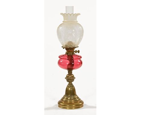 A Victorian brass oil lamp, with etched glass shade and cranberry glass reservoir.  Height including chimney 68 cm.The shade 